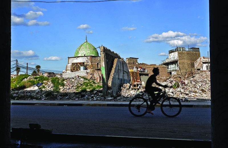 MOSUL: An Iraqi youth rides a bicycle past the Nuri mosque in the old town of the northern city of Mosul, a site heavily damaged by Islamic State (IS) group fighters in the 2017 battle for the city.-AFPn