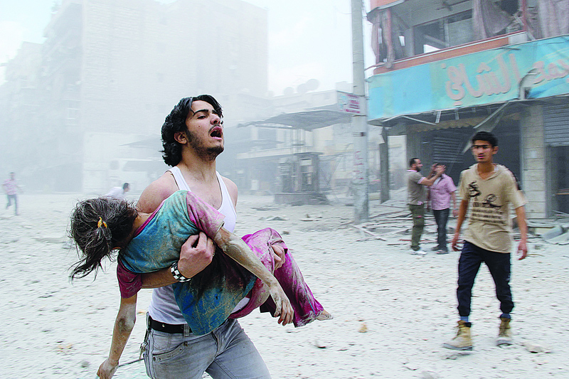 ALEPPO, Syria: In this file photo taken on June 3, 2014, a man carries a young girl who was injured in a reported barrel-bomb attack by government forces in Kallaseh district in the northern city of Aleppo. --/AFPn