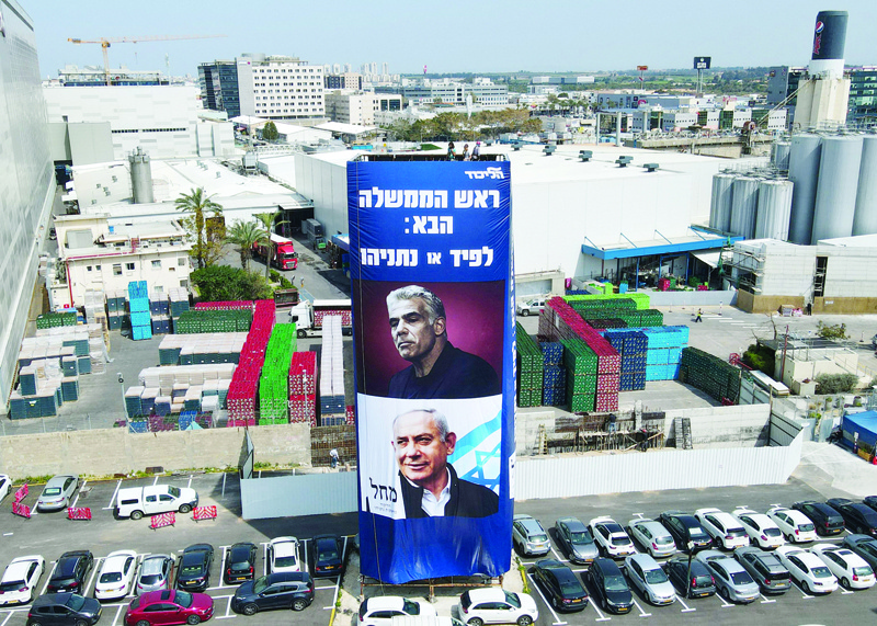 NETANYA, Israel: Workers hang election campaign posters for Israel's Likud party bearing a portrait of its leader Prime Minister Benjamin Netanyahu (bottom), and opposition party leader Yair Lapid (top) on a billboard in the Israeli coastal city of Netanya.-AFP n