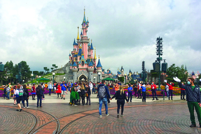 In this file photo Visitors and staff wearing protective face masks, walk down the Main Street of Disneyland Paris in Marne-la-Vallee, near Paris.-AFP n