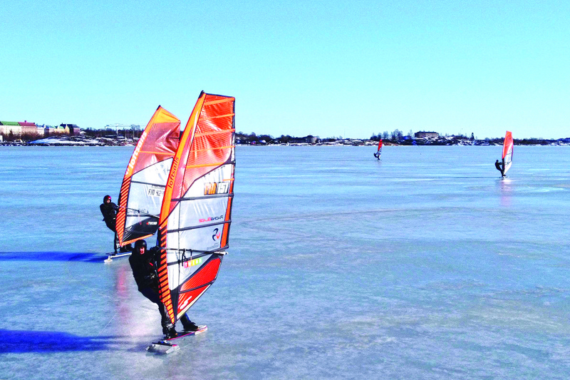 TOPSHOT - An aerial photo taken on February 28, 2021 shows ice surfers skating across the frozen Baltic Sea off the coast of Helsinki. - What to do if you are a windsurfing enthusiast in a country where the sea freezes over for months of the year? For a group of Finns, the answer is to kit out sailboards with skates and take to the ice, reaching speeds of up to 100km/h (62mph) in a burgeoning sport that can only be practised in a handful of places around the world. (Photo by Sam KINGSLEY / AFP) / TO GO WITH AFP STORY