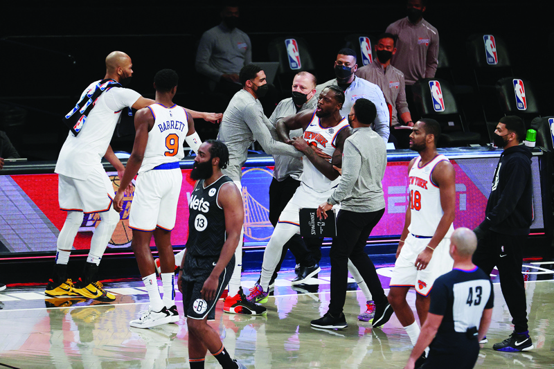 NEW YORK: Julius Randle #30 of the New York Knicks is restrained by teammates after their 117-112 loss against the Brooklyn Nets during their game at Barclays Center on March 15, 2021 in New York City. - AFPn