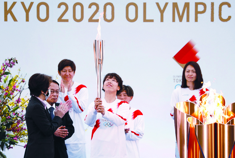 NARAHA, Japan: Tokyo 2020 president Seiko Hashimoto (left) applauds as a member of Japan's women's national football team carries the Olympic torch on day one of the torch relay in Fukushima Prefecture yesterday. - AFP n