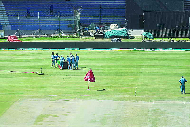 KARACHI: Ground workers leave as the Pakistan Super League (PSL) was suspended after seven players tested positive for COVID-19, at the National Stadium in Karachi yesterday. - AFPn