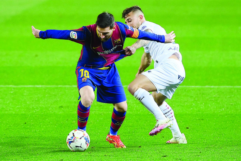BARCELONA: Barcelona's Argentinian forward Lionel Messi challenges Huesca's Spanish defender Pablo Maffeo during the Spanish League football match between Barcelona and SD Huesca at the Camp Nou stadium in Barcelona on Monday. - AFPn