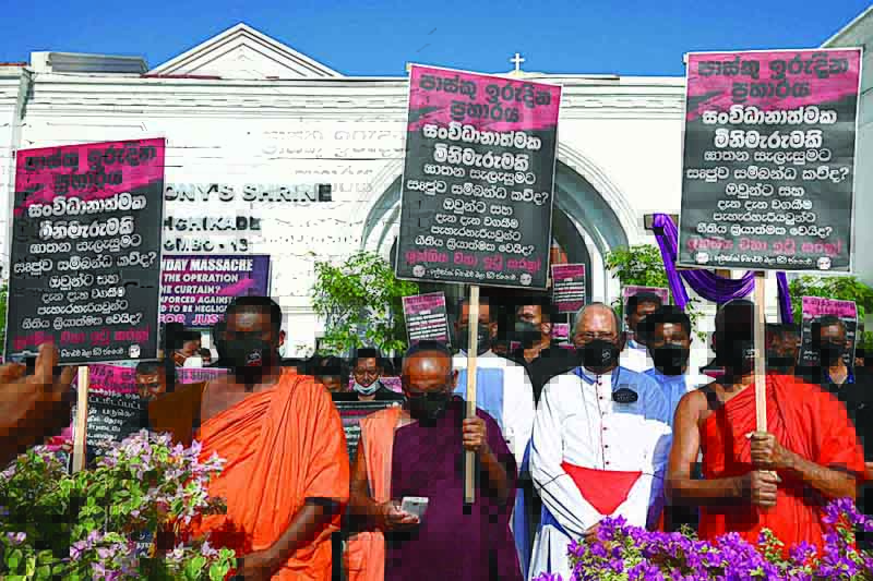 COLOMBO : Sri Lanka's top Catholic priest Cardinal Malcolm Ranjith (front second right) with other Catholics and Buddhist monks take part in a 'Black Sunday' demonstration outside the Saint Anthony's church in Colombo yesterday.-AFP n