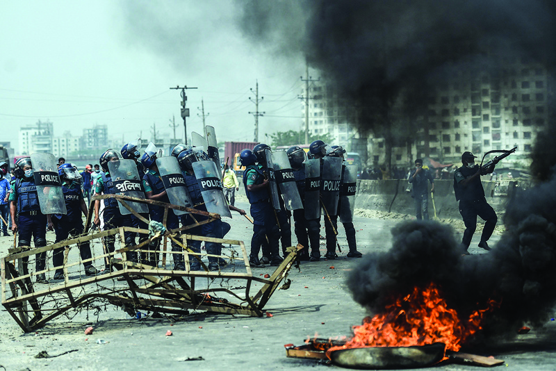 DHAKA: Police personnel march towards activists from Hefazat-e Islam as they block a road during a nationwide strike following deadly clashes with police over Indian Prime Minister Narendra Modi's visit, in Narayanganj yesterday.-AFP n