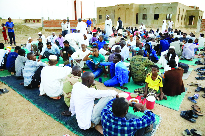 Muslim worshippers break their Ramadan fast along the side of the road of the Jazeera State highway in the village of Al-Nuba, about 50 kilometers south of Sudan's capital. – AFPn