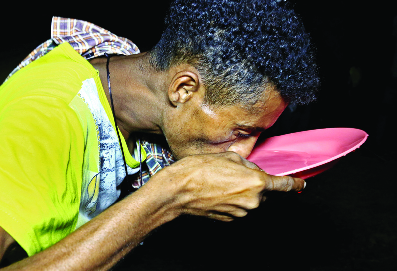 In this file photo, a man drinks water from a plate as Ethiopian refugees who fled fighting in Tigray province camp at the Um Raquba camp in Sudan's eastern Gedaref state. - AFPn