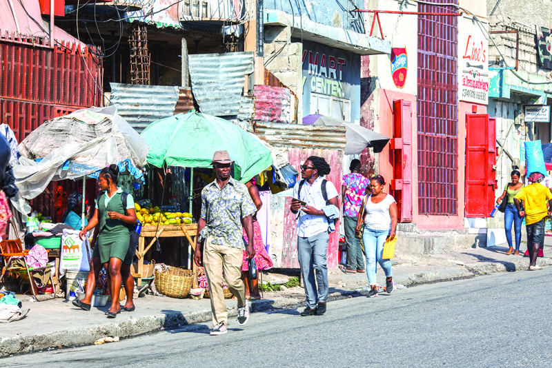 People walk down a street of Port-au-Prince on April 12, 2021. (Photo by Valerie Baeriswyl / AFP)