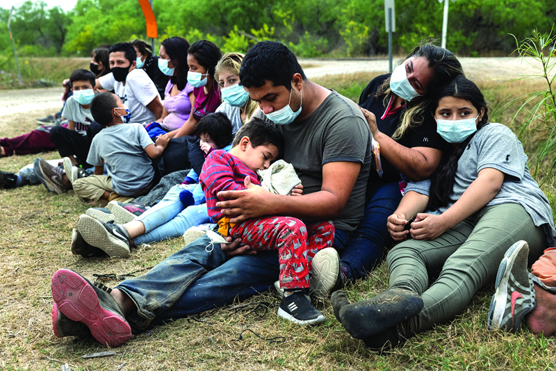 LA JOYA, Texas: A Guatemalan family waits with fellow immigrants to board a US Customs and Border Protection bus to a processing center after crossing the border from Mexico on Tuesday.-- AFPn