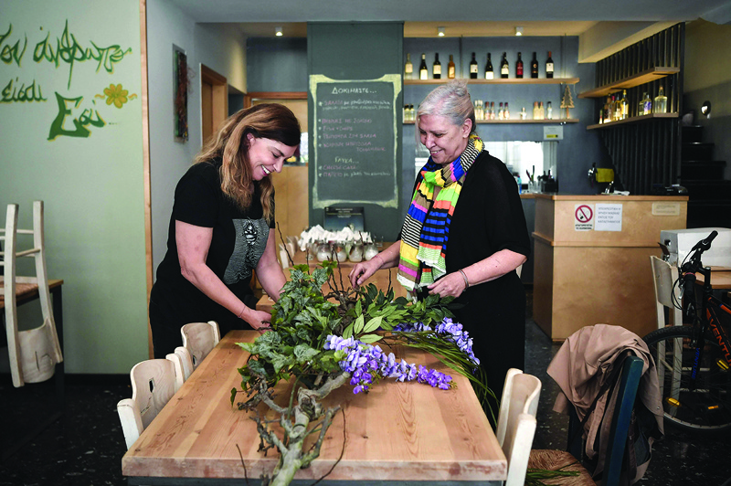 Venetia, owner of a restaurant and her cook Florentia arrange flowers to decorate the restaurant, closed since November 2020, in the trendy Koukaki district of Athens.-AFPn