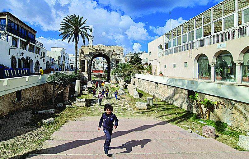 Youths play near the Roman Marcus Aurelius arch in the Libyan capital Tripoli's old city, which is undergoing infrastructure rehabilitation work. - AFPn