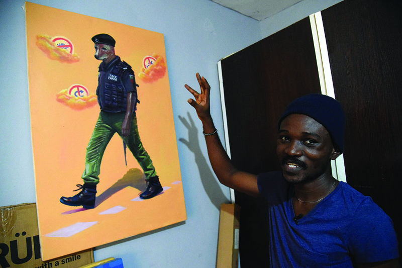 Painter Julius Agbaje points to a painting of police officer with dog head that he titled 'Mad Dog' at his studio residence in Ipaja, Lagos.-AFP photosn