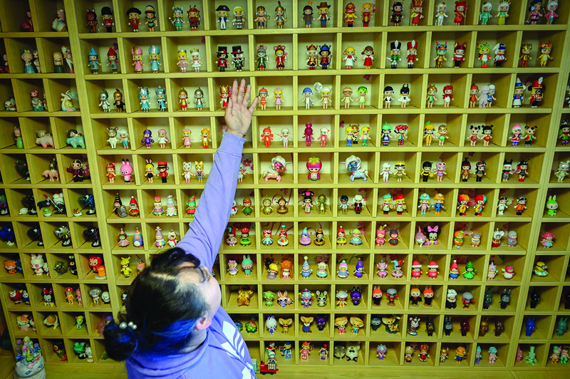 This picture shows music student Wang Zhaoxue showing the “blind box” toys she collected, during an interview at her home in Beijing.n