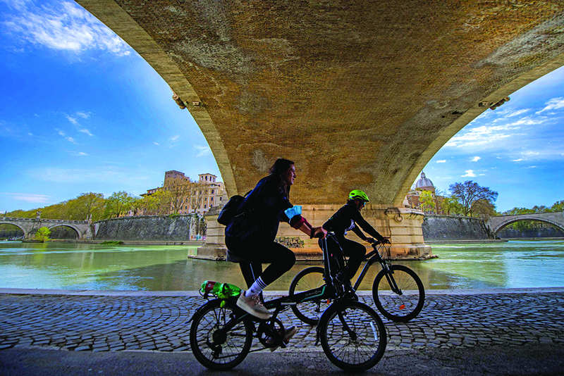 People ride their bicycle along the river Tiber in Rome. -AFP photosn