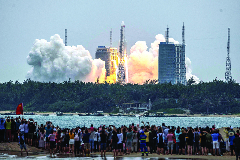 People watch a Long March 5B rocket, carrying China's Tianhe space station core module, as it lifts off from the Wenchang Space Launch Center in southern China's Hainan province yesterday.-AFPn