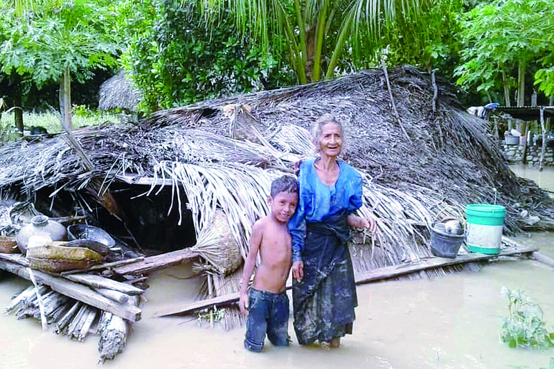 An elderly villager and her grandson stand in floodwaters in front of their damaged home in the village of Haitimuk in East Flores after flash floods and landslides swept eastern Indonesia and neighboring East Timor. - AFPn