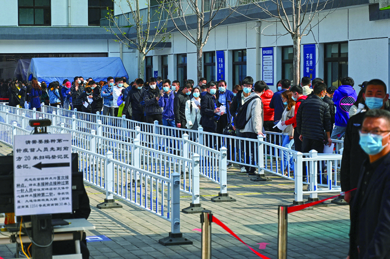 BEIJING: People line up to be vaccinated against the COVID-19 coronavirus, at a vaccination center next to a residential compound in Beijing yesterday.-AFPn
