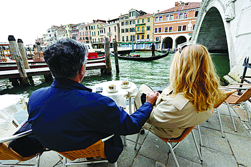 VENICE: A couple has coffee in a bar next to the Rialto bridge in downtown Venice yesterday. - AFP n