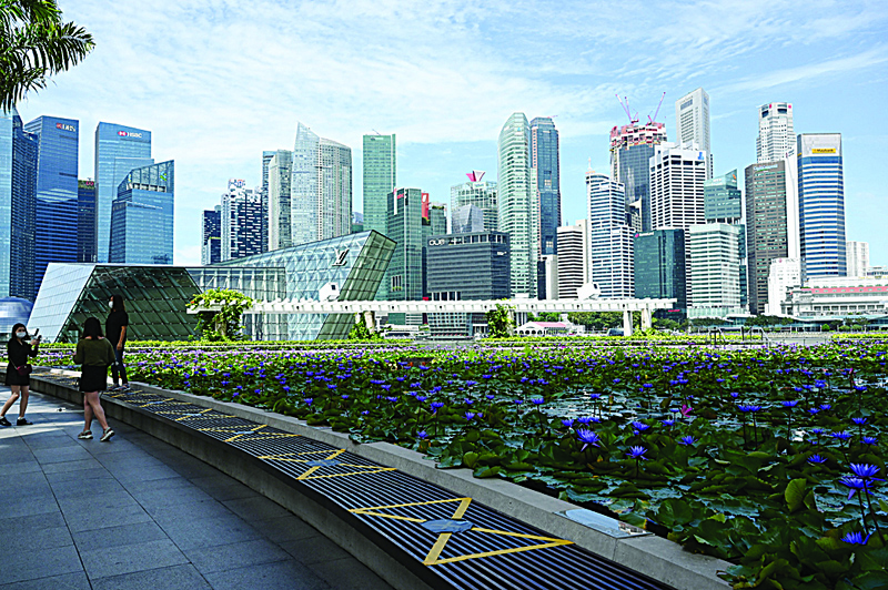 SINGAPORE: People take pictures beside the pond of the ArtScience Museum against the city skyline in Singapore.-AFPn