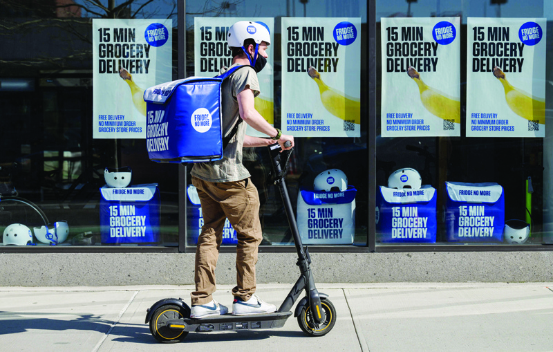 NEW YORK: An employee rides a scooter to deliver groceries from 'Fridge No More' on March 31, 2021 in the Brooklyn borough. - AFP n