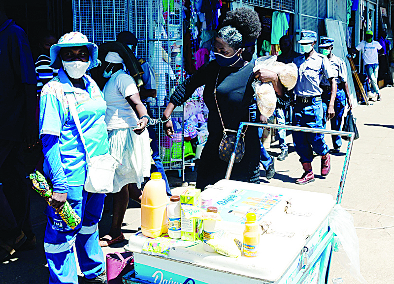 HARARE: Spiwe Tembo, an informal trader who makes her living selling buns, is handcuffed to another vendor after their arrest by police at a busy shopping complex alongside a commuter bus rank on April 15 2021. – AFP n