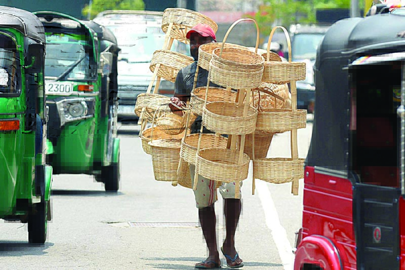 COLOMBO: A street vendor carrying woven reed baskets looks for customers as he walks along a street on April 9, 2021. - AFP n