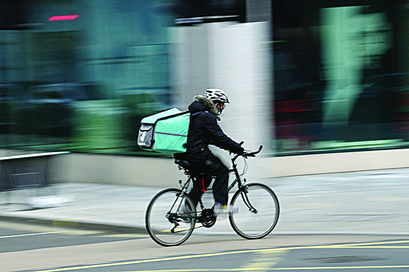 A Deliveroo rider cycles through central London. - AFP