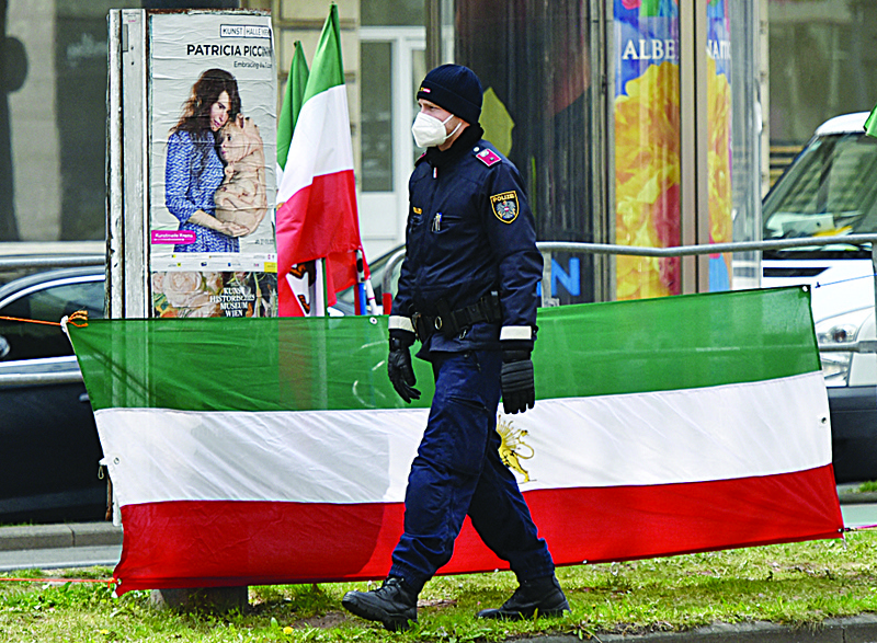 VIENNA: A policeman walks past a flag of the National Council of Resistance of Iran, an Iranian opposition group, during a protest outside of the 'Grand Hotel Wien' during the closed-door nuclear talks with Iran in Vienna where diplomats of the EU, China, Russia and Iran hold their talks. -- AFPnn