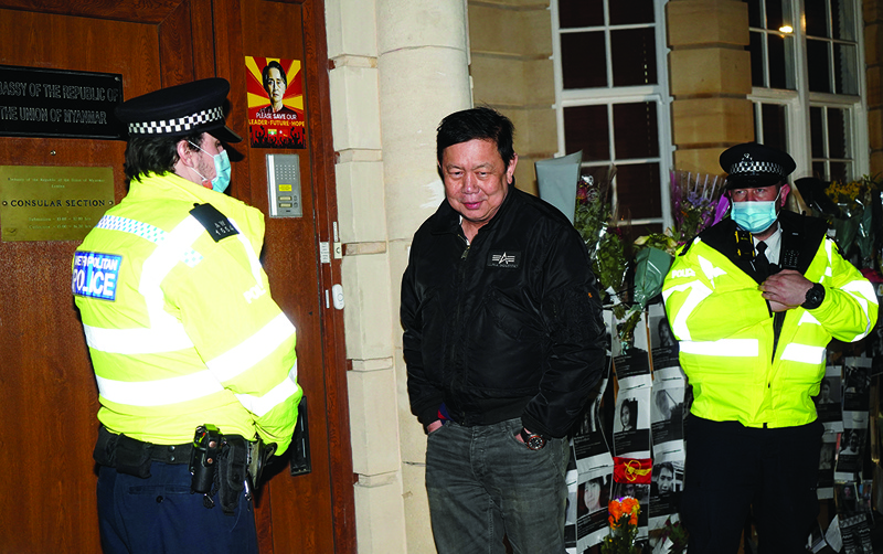 LONDON: Myanmar's Ambassador to the United Kingdom, Kyaw Zwar Minn, stands with police officers locked outside the Myanmar Embassy in London on Wednesday.-AFPn