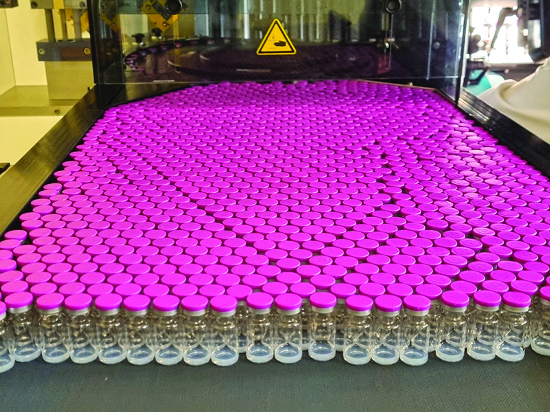 This handout file photograph taken and released by French pharmaceutical subcontracting firm Delpharm shows vials being filled with the Pfizer/BioNTech COVID-19 vaccine on a production line at the Delpharm plant in Saint-Remy-sur-Avre, northern France. - AFPn