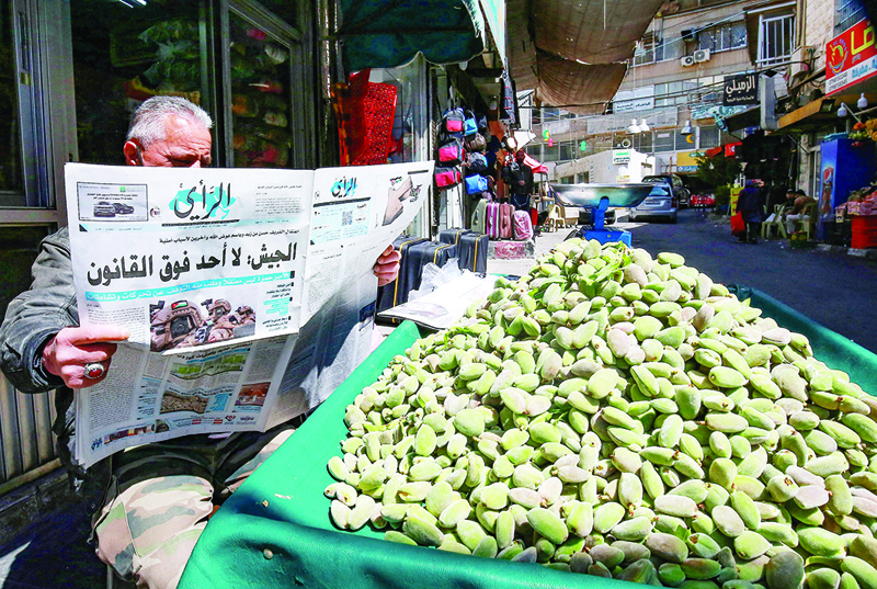 AMMAN: A Jordanian street vendor reads a local newspaper yesterday with a headline on its front page reading 'Army: No one is above the law'. - AFP  n