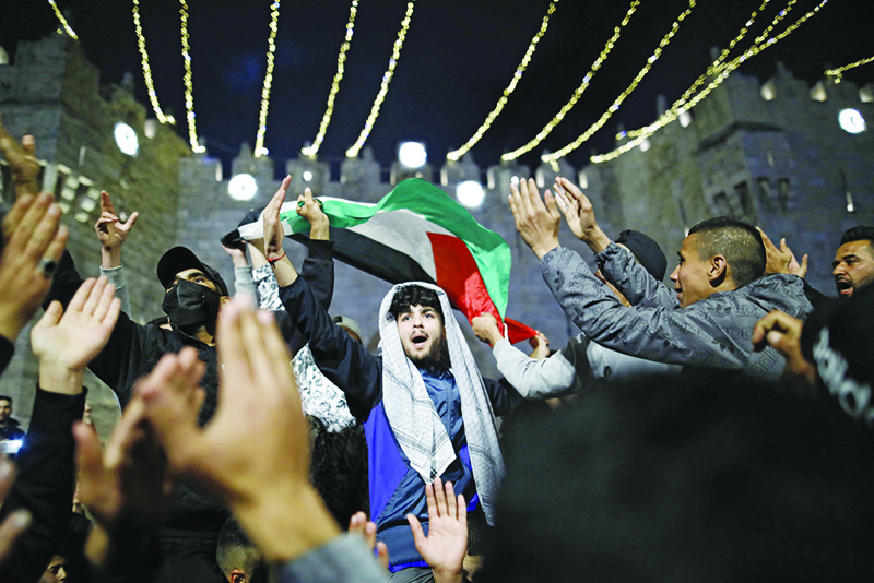 JERUSALEM: Palestinian protesters wave the national flag outside the Damascus Gate in Jerusalem's Old City Monday.-AFPn