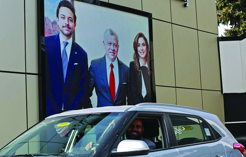 AMMAN: A car drives past a billboard bearing portraits of King Abdullah II, Queen Rania and their son Crown Prince Hussein on a street in the capital yesterday. - AFP n