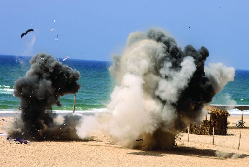 GAZA CITY: Smoke rises from explosions during a military drill by members of the Mujahideen Brigades, the armed wing of the Palestinian movement of the same name, along the beach in Gaza City yesterday.-AFPn