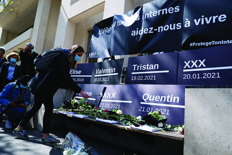 PARIS: Medical interns and families lay flowers below a banner reading ‘The hospital is killing his interns, help us live’ as they pay homage to colleagues and relatives during a demonstration in front of the French Health Ministry to denounce the heavy workload yesterday. — AFP