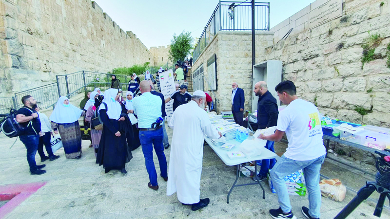 JERUSALEM: This archive photo shows people distributing food during a Kuwait-funded campaign to give away iftar meals in Ramadan this year. - KUNAn