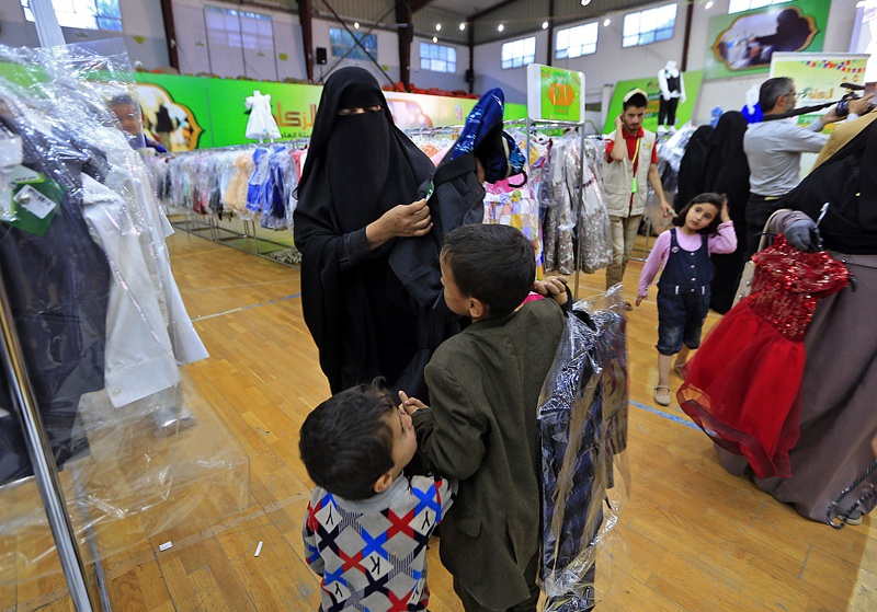 SANAA, Yemen: Yemeni children carry new outfits during a charity distribution of clothes at a stadium, as part of actions to help the impoverished during the Muslim holy fasting month of Ramadan Sunday.-AFPn