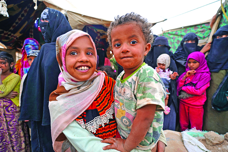 MARIB, Yemen: A girl carries a boy as she stands near other women and children by tents at the Suweida camp for people internally displaced by conflict, near Yemen's northern city of Marib.-AFPn