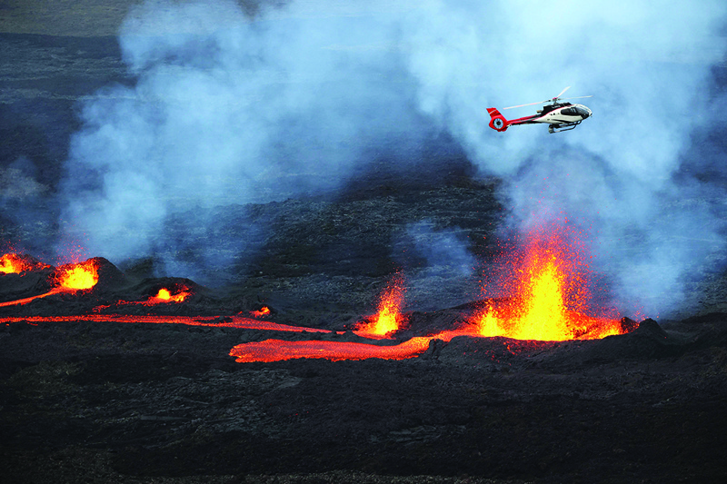 Photo shows a helicopter flying as lava is erupting from Piton de la Fournaise volcano. - AFPnn