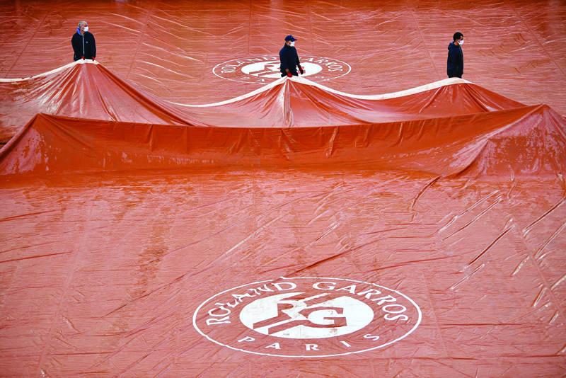 PARIS: In this file photo taken on October 4, 2020, groundstaff members remove covers across the Suzanne Lenglen court surface after the rain, on Day 8 of The Roland Garros 2020 French Open tennis tournament in Paris. - AFPn