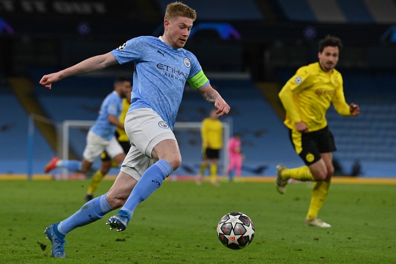 Manchester City's Belgian midfielder Kevin De Bruyne (L) runs with the ball during the UEFA Champions League first leg quarter-final football match between Manchester City and Borussia Dortmund at the Etihad Stadium in Manchester, north west England, on April 6, 2021. - AFP