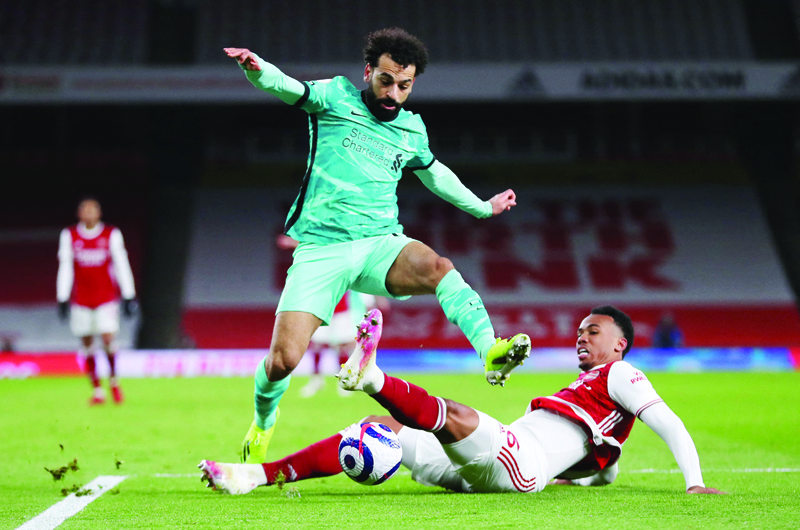 LONDON: Liverpool's Egyptian midfielder Mohamed Salah (center) jumps over a challenge from Arsenal's Brazilian defender Gabriel (right) during the English Premier League football match between Arsenal and Liverpool at the Emirates Stadium in London on April 3, 2021. - AFPn