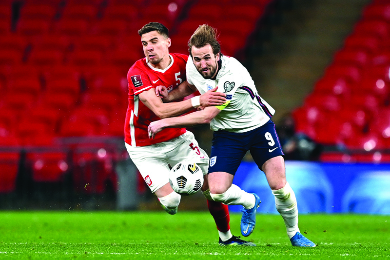LONDON: England's striker Harry Kane (right) tangles with Poland's defender Jan Bednarek (left) during the FIFA World Cup Qatar 2022 Group I qualification football match between England and Poland at Wembley Stadium in London on March 31, 2021. - AFPn