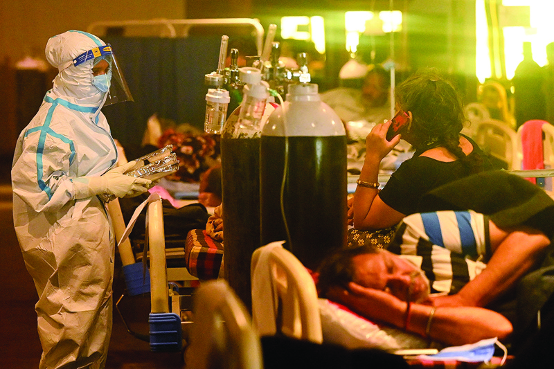 NEW DELHI: Health workers wearing personal protective equipment (PPE kit) attends to COVID-19 coronavirus positive patients inside a banquet hall temporarily converted into a COVID care center in New Delhi yesterday.—AFPn