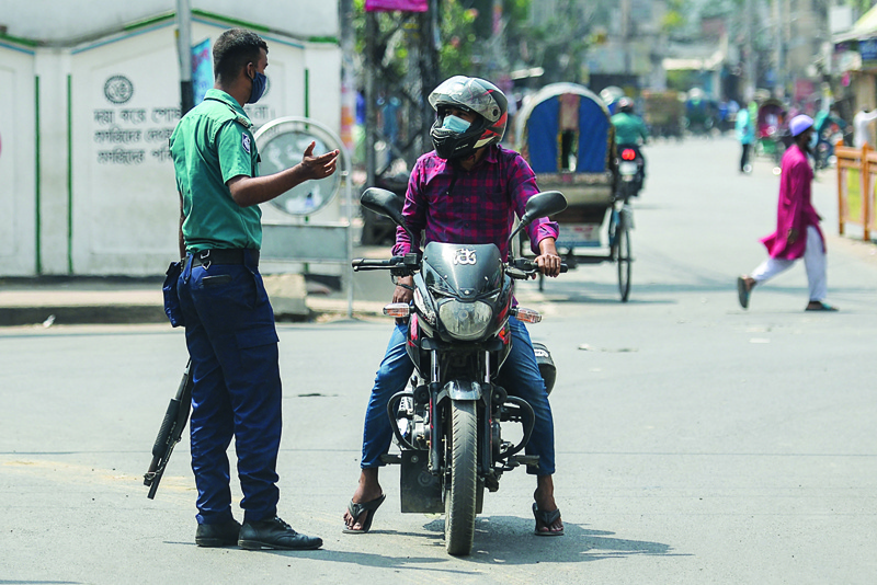 DHAKA: A policeman stops a motorist at a checkpoint as Bangladesh's authorities enforced a strict lockdown to combat the spread of the COVID-19 coronavirus, in Dhaka yesterday. - AFPn