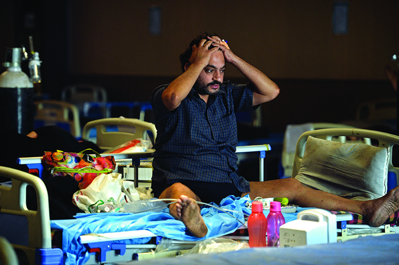 NEW DELHI: A COVID-19 coronavirus patient reacts while sitting on a bed inside a banquet hall temporarily converted into a COVID care center in New Delhi yesterday.—AFPn