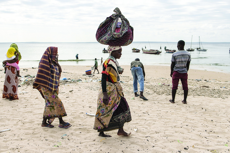 PEMBA: A woman carries her belongings off a boat as she arrives at Paquitequete beach in Pemba after fleeing Palma by boat with forty nine other people. - AFPn