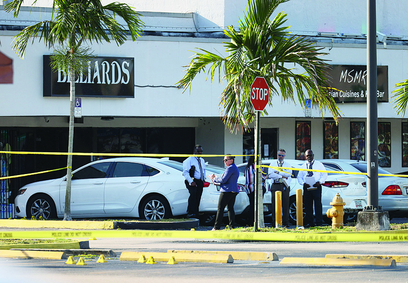 HIALEAH, UNITED STATES: Miami-Dade police investigate near shell case evidence markers on the ground where a mass shooting took place outside of a banquet hall yesterday in Hialeah, Florida. n